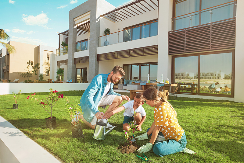 a kid and his parents are watering flowers in the garden of hawana lagoon Villas at Hawana Salalah Oman